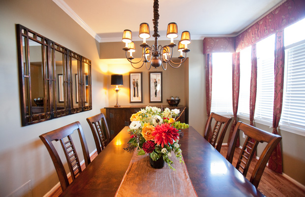 Dining room with wooden table, chandelier, floral centerpiece, and curtained windows, warm earthy tones, cozy elegant mood